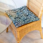 Rattan-Stuhl mit gemustertem Kissen auf Holzboden