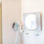 Badezimmer mit Spiegel und Duschkopf an der Wand