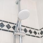 Duschbrause mit Chromarmatur und Mosaikfliesen an der Wand
