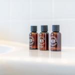 Drei kleine Flaschen mit Badprodukt auf einer weißen Oberfläche.