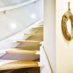 Staircase with white steps and straw-colored step mats. A woven ring hangs on the wall.