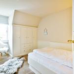 Bedroom with bed, wardrobe, and chair by the window.