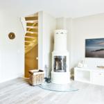 Living room with white fireplace, TV, and wooden floor. Stairs lead upstairs.