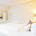 Bedroom with white bed, nightstand, lamp, and built-in TV.