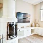 Living room with white fireplace, TV, and window with lamp.