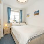 Bedroom with bed, nightstand, and window with blue curtains.