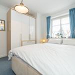 Bedroom with bed, wardrobe, and window with blue curtains.