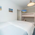 Bedroom with double bed and two-tiered mattress, next to a bunk bed with wooden frame.