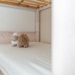 A bed with two stuffed sheep and a wooden frame.