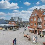 Market square with shops, benches, and a red brick building.