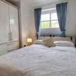 Bedroom with bed, wardrobe, and window with curtains.