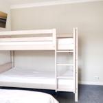 Room with bunk bed, TV, and gray carpet flooring.