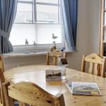 Wooden table with chairs, window with curtains, and glass cabinet in dining room.