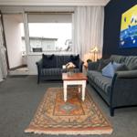 Wohnzimmer mit Sofa, Couchtisch und Teppich. Fenster und Balkon sind sichtbar.