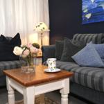 Zwei Sofas mit Kissen, Tisch mit Blumen und Tasse, Wandbild und Lampe.