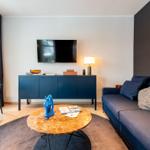Wohnzimmer mit Sofa, Couchtisch und Fernseher an der Wand.
