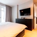 Schlafzimmer mit Bett, TV und Blick auf Balkon.