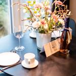 Runder Tisch mit Blumenvase, Weinflasche und Geschirr vor Fenster