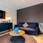Wohnzimmer mit Sofa, Couchtisch und Fernseher an der Wand.