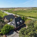 House with dormers and garden, surrounded by meadows and forest.