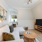 Living room with sofa, TV, and wooden table. Window with view outside.