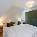 Bedroom with bed, green wardrobe, and nightstand under sloped ceiling.