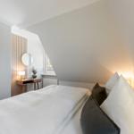 Bedroom with sloped ceiling, bed, nightstand, and mirror.