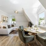 Living and dining area with sofa, table and chairs under sloped ceilings.