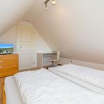 Schlafzimmer mit Doppelbett, Schreibtisch und Fernseher auf Schrank.