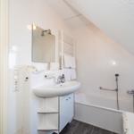 Badezimmer mit Badewanne, Waschbecken und Spiegel. Dachschrägen und weiße Fliesen.