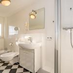 Badezimmer mit Dusche, Waschbecken und Toilette. Schwarzes und weißes Fliesenmuster.