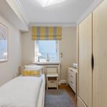 Ein Schlafzimmer mit Bett, Kleiderschrank und Fenster mit Blick aufs Meer.