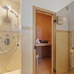 Dusche mit Duschbrause und Sauna mit Holzwand