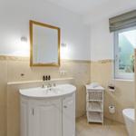 Badezimmer mit Waschbecken, Spiegel, Toilette und Fenster