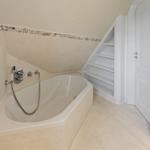 Bad mit Badewanne, Steinverkleidung und eingebautem Regal