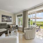 Wohnzimmer mit Sofa, Sessel und Blick auf Terrasse mit Garten.