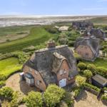 Dorfhaus mit Strohdach und Garten, Blick auf Strand und Watt.