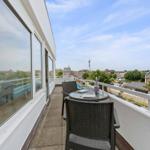 Terrace with table and chairs, view of city and tower.