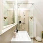 Bathroom with shower, sink, and mirror. Wooden cabinet with anchor decoration.