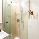Bathroom with shower, sink, and mirror. Decorative vase and soap.