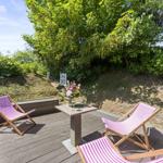Terrace with three deck chairs and table under trees.