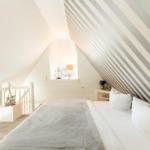 Bedroom with sloped ceiling, bed, nightstand, and window.