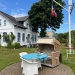 Haus mit Garten, Strandkorb und Tisch. Flagge weht im Wind.