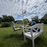 Garten mit Tisch, Stuhl und Segelboot auf Mast. Flagge weht im Wind.