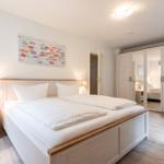 Schlafzimmer mit Doppelbett, Nachttisch und Kleiderschrank.