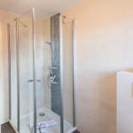 Dusche mit Glaswand und Mosaikfliesen, Toilette und Badewanne