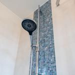 Duschkopf mit Chromarmatur und Mosaikfliesenwand