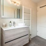 Badezimmer mit Waschtisch, Spiegel und Dusche