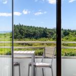 Balkon mit Tisch und Stühlen bietet Blick auf grüne Landschaft und Meer.