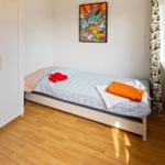 Ein Schlafzimmer mit Bett, Kleiderschrank und Fenster mit Vorhang.